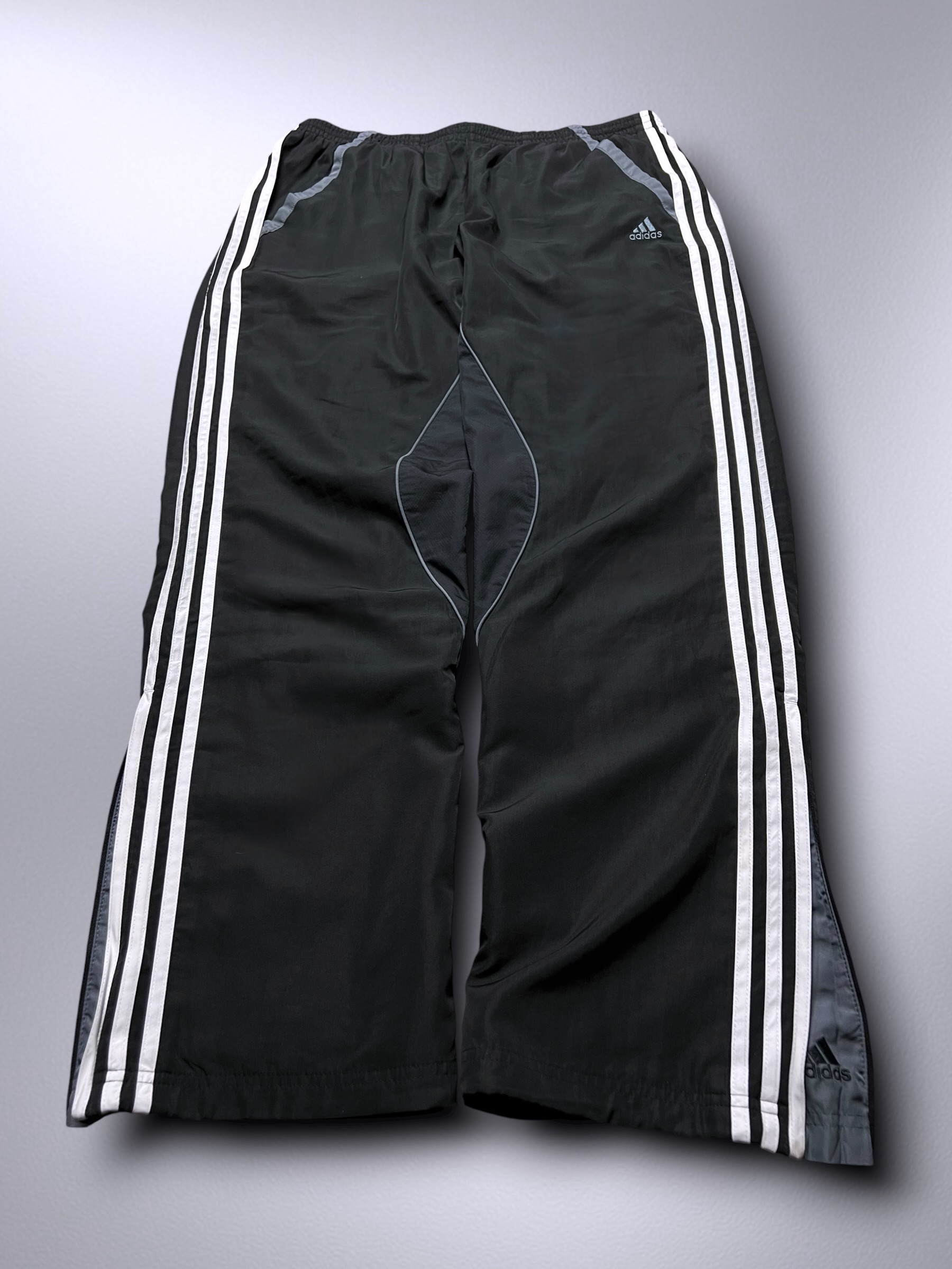 Schwarze Adidas-Trackpants mit weißen Streifen und grauen Kontrastnähten