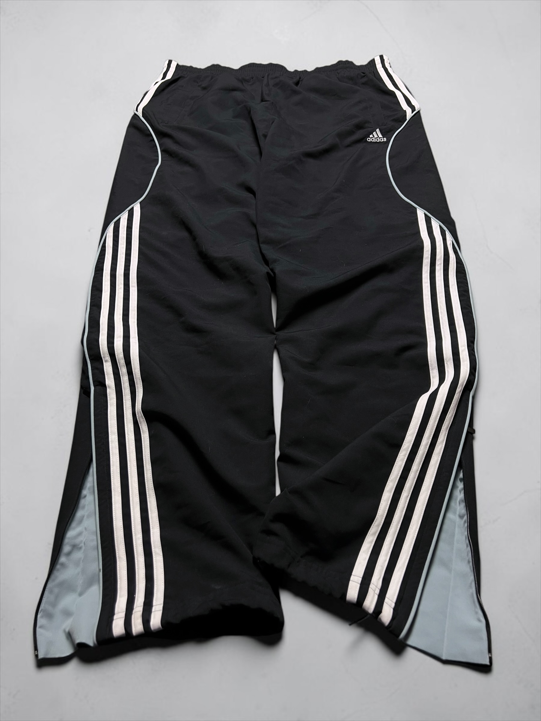 Schwarze Adidas-Trackpants mit weißen Streifen und hellgrauen Seiteneinsätzen
